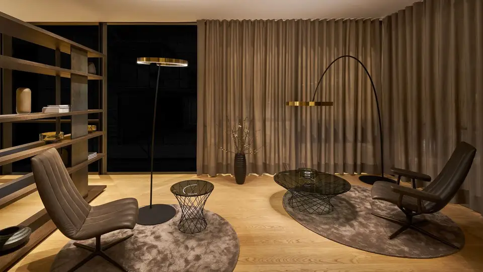 Twee Occhio-vloerlampen met messing ringen in een zitkamer bij avond